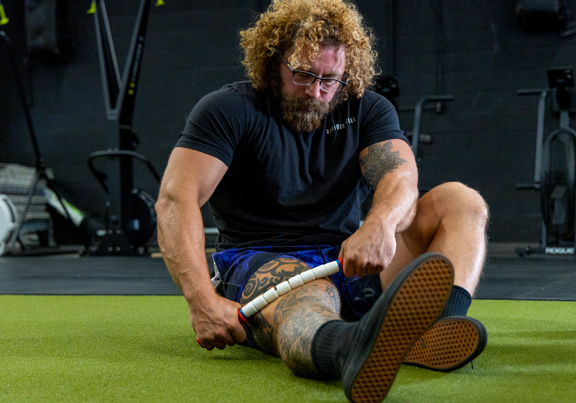 Person sitting on green turn using the Travel Stick to massage their outer quads