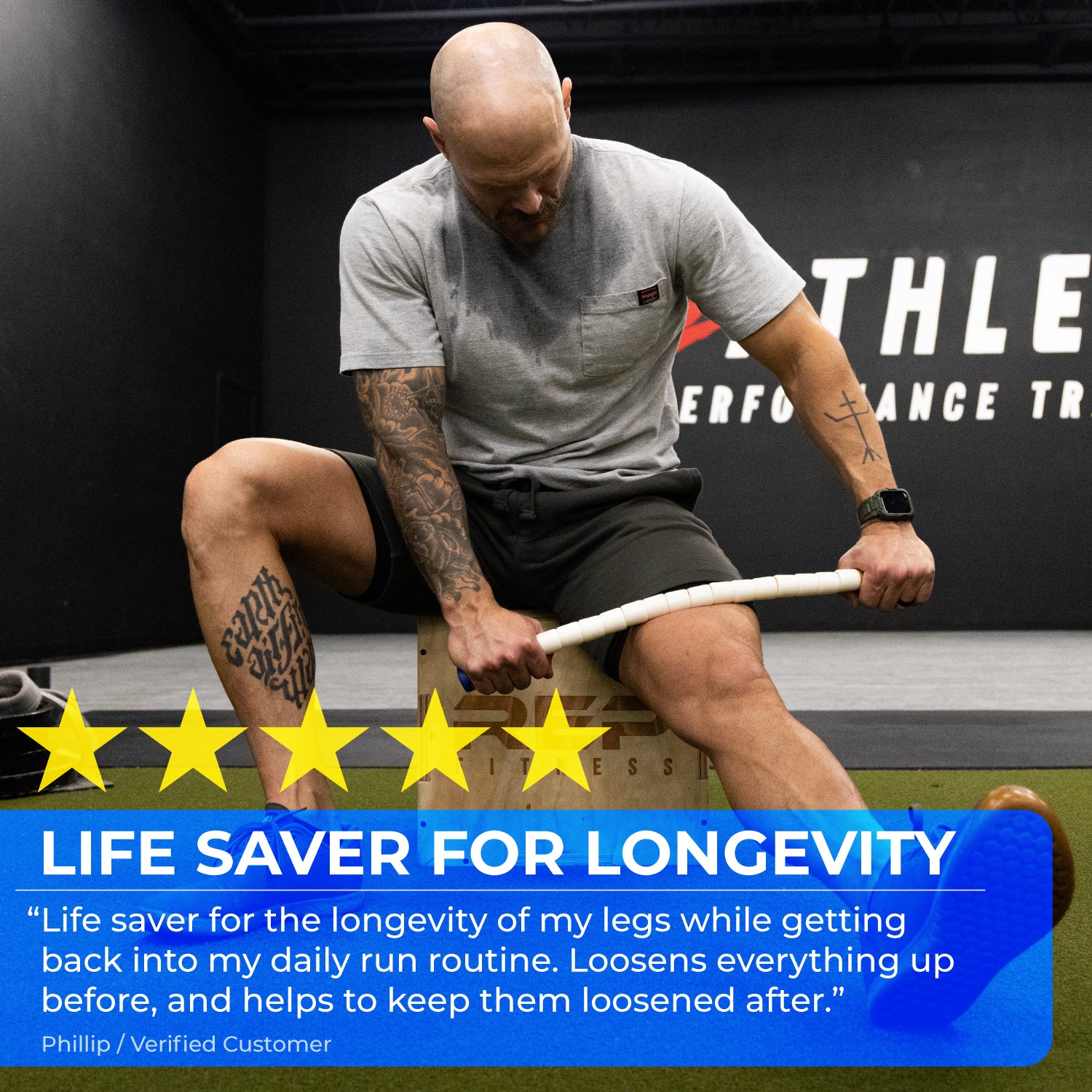 A man sits on a wooden box in a gym, using the 24 Body Stick on his thigh. Five yellow stars and a review appear at the bottom, praising its benefits for running recovery.