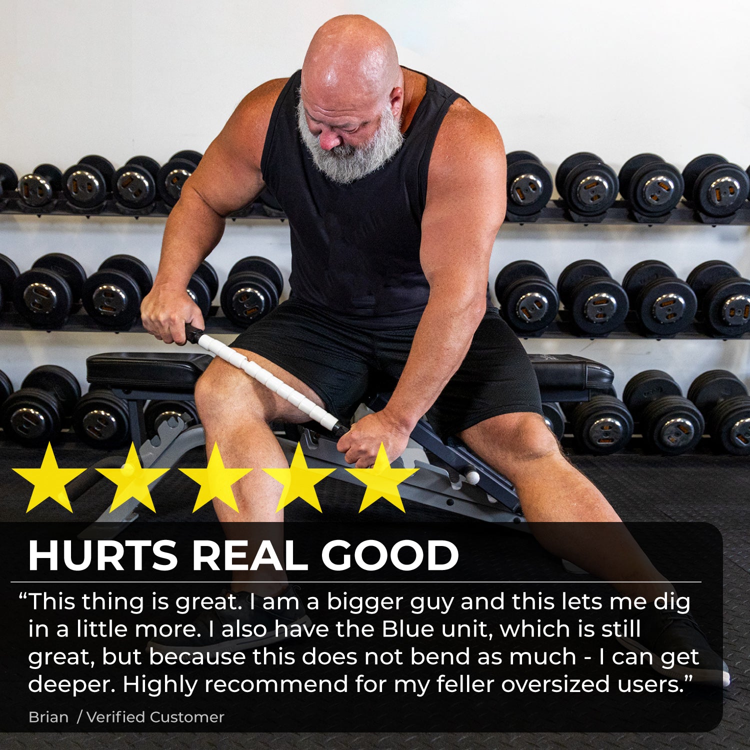A muscular, bearded man uses the Stiff Stick - 24 muscle roller on his thigh while seated on a gym bench amid dumbbells. Five yellow stars and a glowing customer review praising the product appear overlaid on the image.